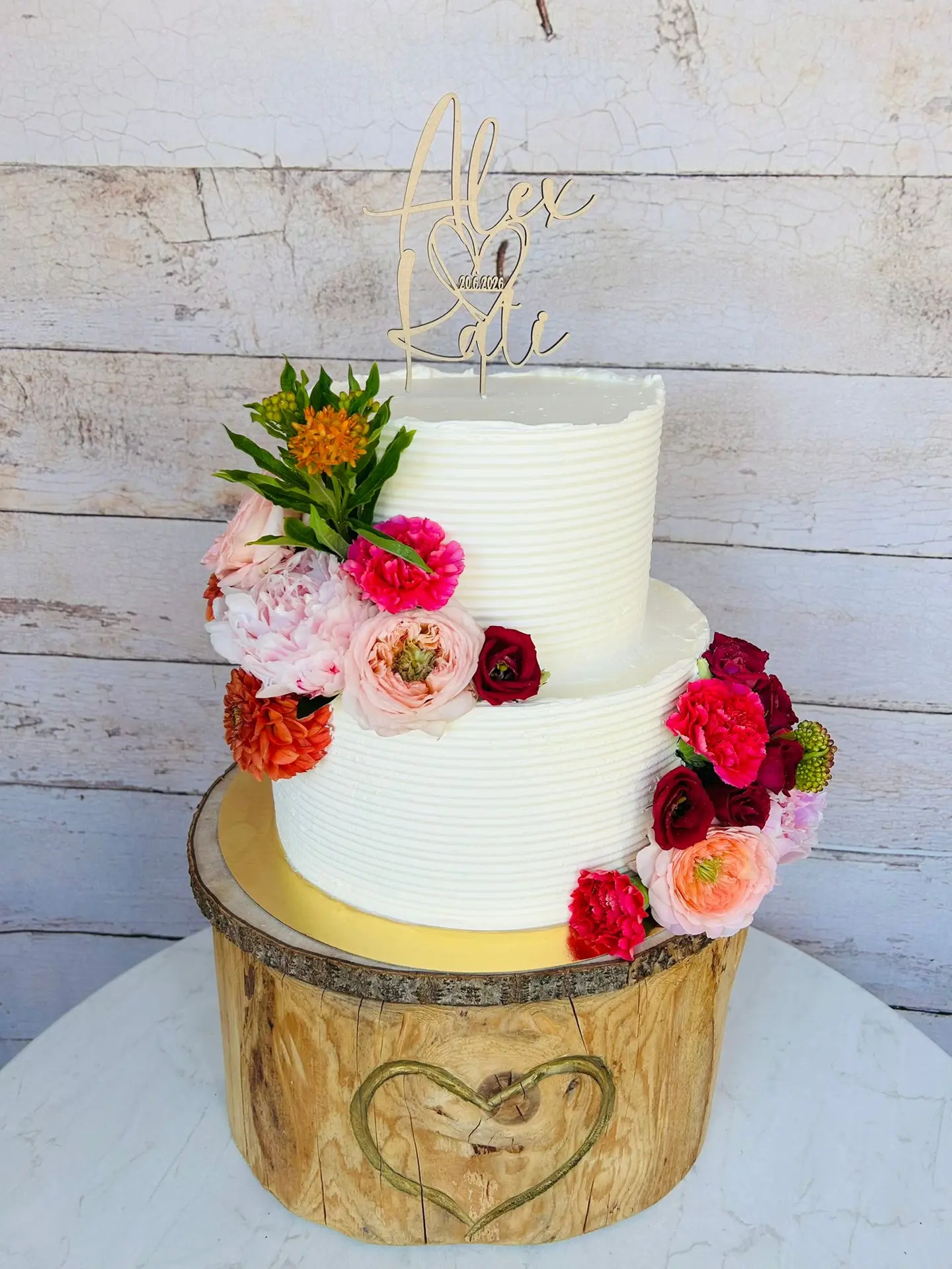 Zweistöckige Hochzeitstorte mit pinker Blumenkaskade und Holz-Topper